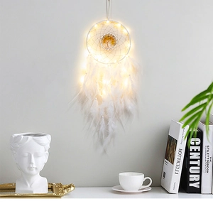 Detailed close-up of a glowing white dreamcatcher with warm LED lights and feathers