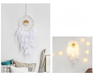 Detail of white handmade dreamcatcher with golden tree motif and soft feathers