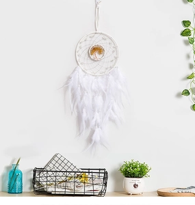 Detail of white feather dreamcatcher with golden tree of life against a white wall