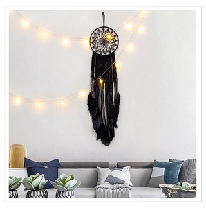 Detail of black bohemian dream catcher with feathers hanging on wall in cozy room setup