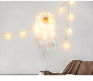 Detail of white feather dreamcatcher with warm LED lights in a cozy home setting