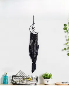 Detail of handmade black moon dreamcatcher with feathers and beads on a white wall
