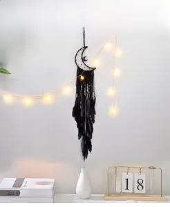 Detail of black bohemian moon dream catcher with feathers and warm led string lights