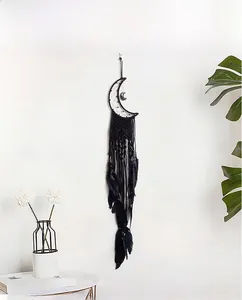 Detail of moon-shaped dream catcher with black feathers and woven ropes on a white wall