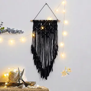 Handmade black macrame wall hanging with feathers and wooden rod for boho home decor