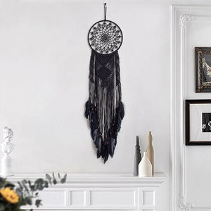 Large black bohemian dream catcher wall hanging with feathers and woven details on white wall