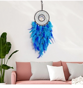 Detailed blue feather dreamcatcher with tree of life crystal stone on a white wall