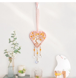 Detail of pink woven heart-shaped tree of life wall decor with crystal prisms and stars