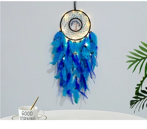 Dreamcatcher with blue feathers and life tree hanging in a cozy home setting with LED lights
