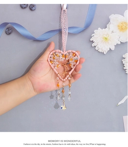 Macro detail of heart-shaped tree of life charm with rose quartz and crystal prisms