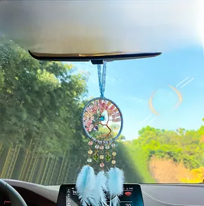 Detail of tree of life car charm with light blue feathers and beads on rear view mirror
