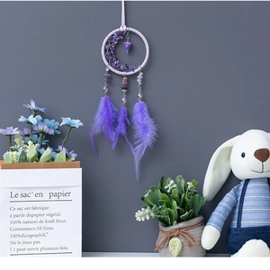Detail of a purple moon dreamcatcher with natural stones and soft hanging feathers