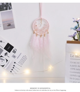Detailed close-up of pink dreamcatcher with natural crystal stones and soft feathers