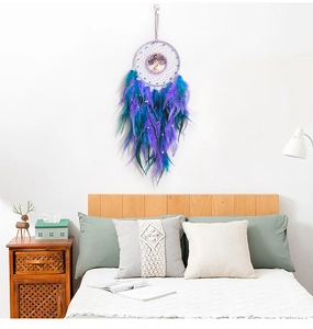 Dreamcatcher wall hanging with purple Tree of Life design and feathers in a cozy bedroom