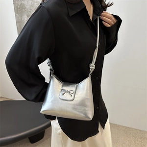 Petit sac à bandoulière argenté métallisé avec nœud papillon porté par un mannequin