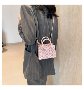 Pink crossbody bag with letter M pattern shown on a model in a gray suit outfit