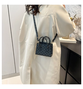 Rear view of model wearing a black mini square bag with M-pattern texture and long strap
