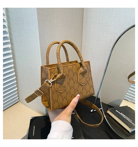 Dettaglio borsa shopper marrone con stampa a motivo M e finiture in oro lussuoso
