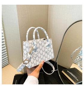 Dettaglio della piccola borsa tote bianca con monogramma M e finiture in oro lucido