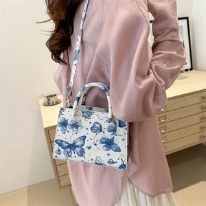 White butterfly pattern shoulder bag with adjustable strap shown in a casual lifestyle setting