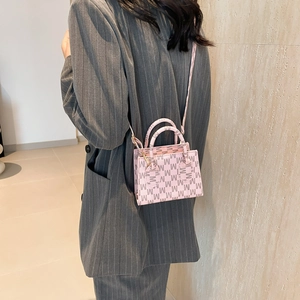 Borsa a tracolla rosa con motivo M mostrata su una modella in blazer a righe
