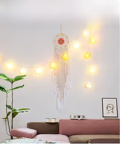 Detail of bohemian handmade crochet dreamcatcher with orange accents and white feathers