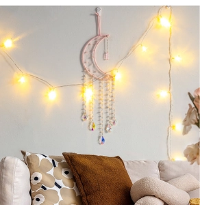 Detail of pink moon dreamcatcher with crystal beads and intricate weaving on a white wall