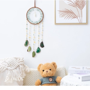 Close-up of a wall-mounted dreamcatcher featuring green agate slices and white mesh webbing