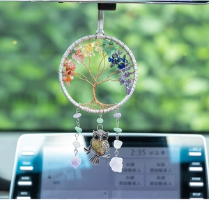 Macro detail of a silver Tree of Life car pendant with seven chakra stones and owl charm