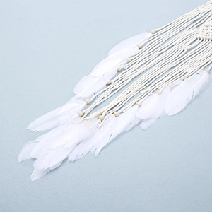 Bohemian crochet wall hanging with white feathers and natural wood beads on blue wall