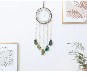 Bohemian dream catcher with green agate slices and natural stone beads on a white wall
