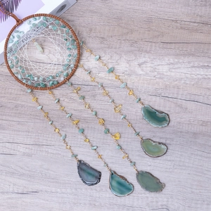 Dreamcatcher wall hanging with natural agate slices and green gemstones on grey wood