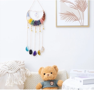 Detail of a seven chakra moon wall hanging with polished gemstones and hanging bells