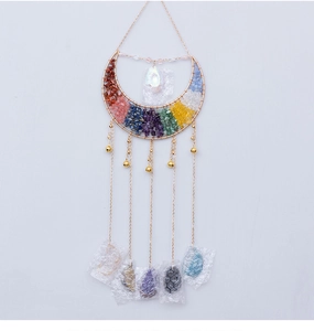 Detail of moon-shaped crystal wall decor with colorful raw stones and hanging bells