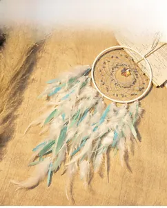 Detail of bohemian dream catcher with soft light blue and white feathers on wood