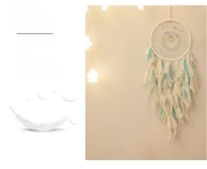 Detail of a white dream catcher with blue feathers and starry lights on a beige wall