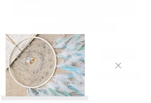 Detail of handmade dream catcher featuring white feathers and crystals for room decor