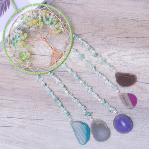 Tree of life wall hanging with green crystals and colorful agate slices on wood