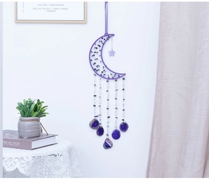 Detail of a purple crescent moon dreamcatcher with amethyst stones and hanging agate slices