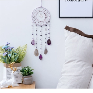 Attrape-rêves artisanal avec tranches d'agate violette suspendu sur un mur blanc
