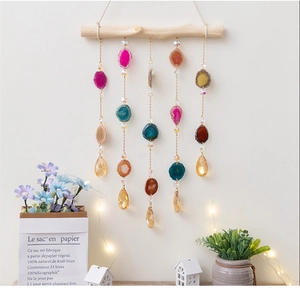 Detail of hanging agate slices and crystal prisms on gold chains with natural wood