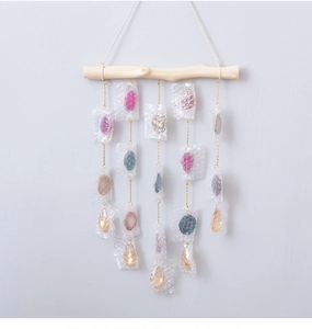 Detail of colorful agate stone wind chime with natural wood branch and gold chains