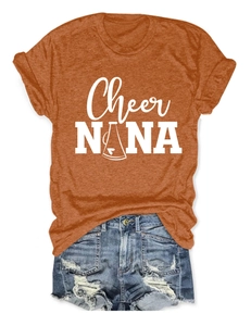 Flat lay of burnt orange crew neck T-shirt with white graphic print and denim shorts