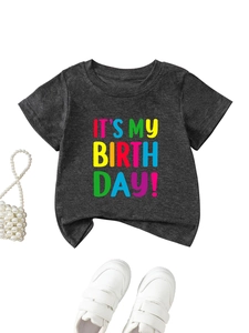 Flat lay of a grey birthday kids t-shirt with colorful text and styling accessories