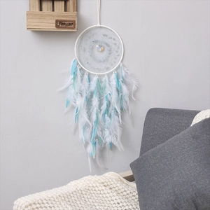 Bohemian blue and white feather dream catcher hanging on a minimalist gray wall