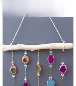 Detail of agate wind chime with colorful natural stone slices and gold chains on wood bar