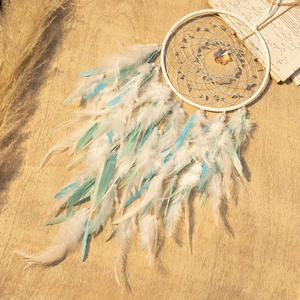 Nordic dreamcatcher with white and mint blue feathers on a natural wood background