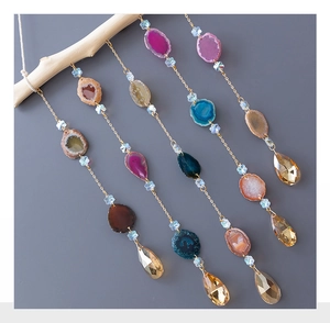 Detail of colorful agate slices and crystal prisms hanging on a wooden branch decor