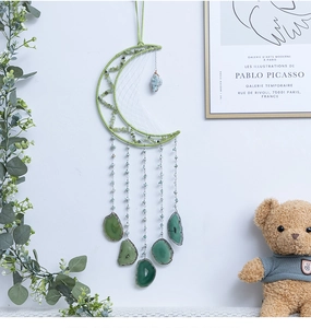 Detalle de atrapasueños lunar hecho a mano con rodajas de ágata verde y piedras naturales