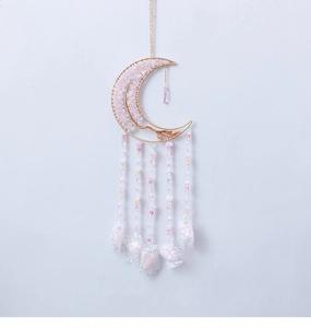 Macro shot of moon-shaped golden wire wall decor with pink crystal stones and beads
